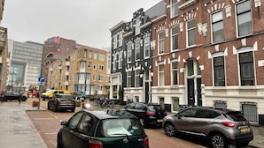 Une rue bordée de voitures garées et d’immeubles.