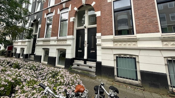 Une rangée de maisons de ville de style victorien, construites en briques, dotées de grandes fenêtres et de décorations ornementales.