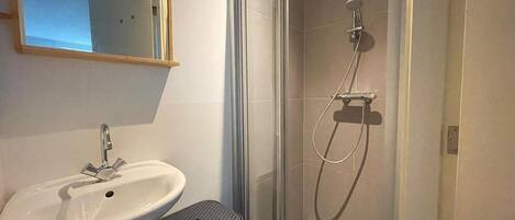 A bathroom with a white sink, a mirror, and a glass-enclosed shower area.