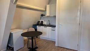 Une cuisine de taille réduite avec une table à manger, des placards blancs et une porte.