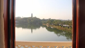 A tranquil lake with a pagoda on a hill, surrounded by trees and a fence. - Huizhou Hotel (Huizhou)