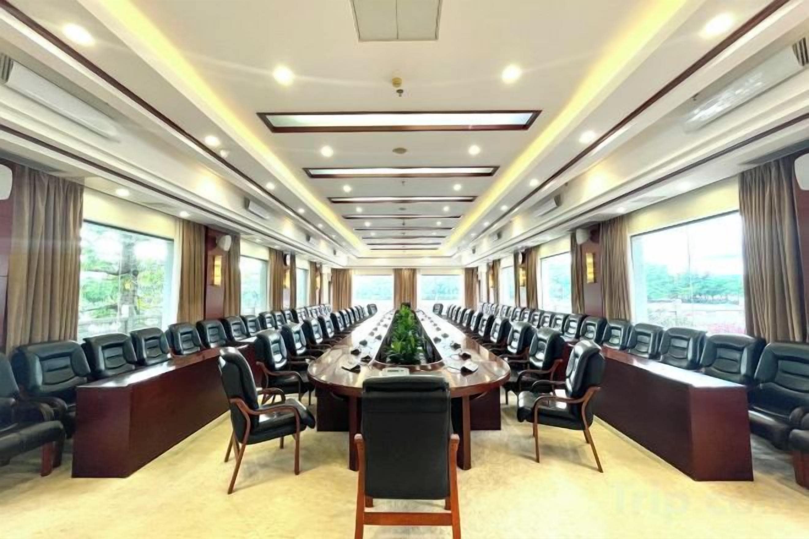 A conference room with a long table, multiple chairs, and large windows.