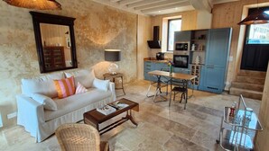 A spacious living area with a white sofa, a wicker chair, a coffee table, and a kitchen in the background. - Casa Pertica  (Ceton)