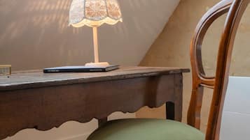 En træstol med grøn pude, et bord med lampe og et ovenlys.