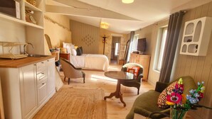 A cozy hotel room with a bed, a dining table with chairs, a small kitchen area, and a living area with a sofa and a TV. - Casa Pertica  (Ceton)