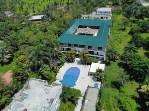 An aerial view of a building with a green roof surrounded by lush greenery, including palm trees. - Hotel Residence La Marsu (Cap Skirring)