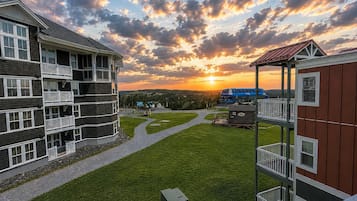 Ein mehrstöckiges Gebäude mit Balkonen, einem grünen Innenhof und Blick auf den Sonnenuntergang.