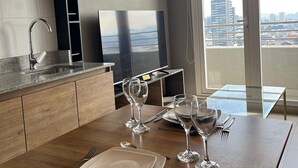 Eine moderne Küche mit Essbereich, einem großen Fenster und Stadtblick sowie einer Pendelleuchte über dem Tisch.