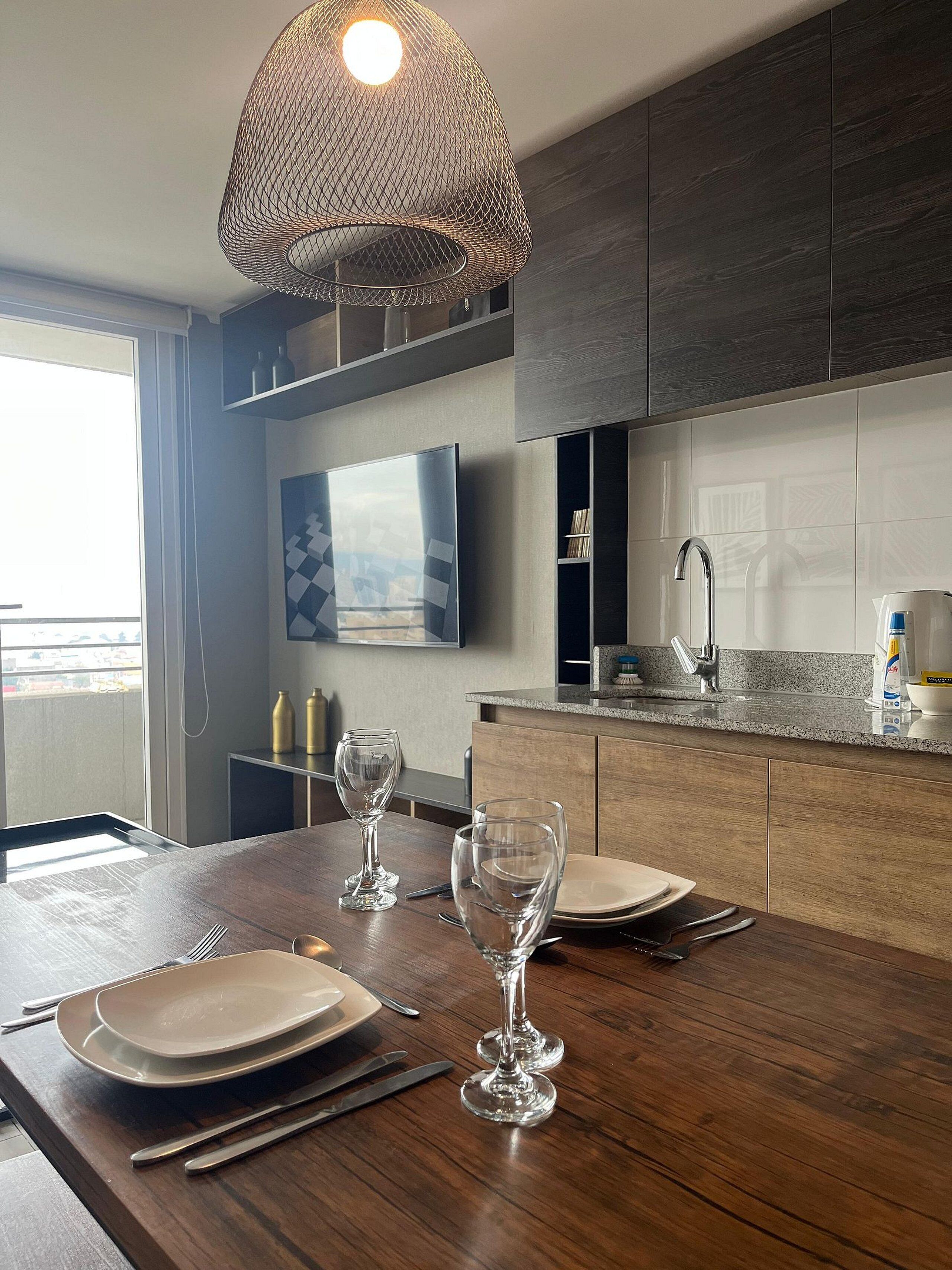 Una cocina moderna con armarios de madera oscura, encimera de granito y una lámpara colgante.