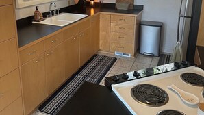 A kitchen with wooden cabinets, a black countertop, a white stove, and a window with a view of greenery.