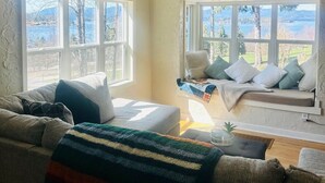 A cozy living room with a couch, a window seat, and a view of the outdoors.