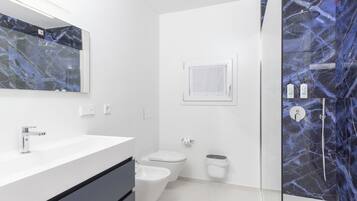 A modern bathroom with a white vanity, a glass shower enclosure, and a bidet.