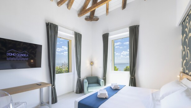 A modern hotel room with a bed, a desk, a chair, and a TV mounted on the wall. - DOMO CICINDELA (Carloforte)