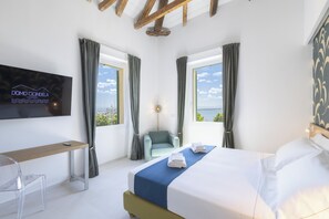 Ein modernes Hotelzimmer mit einem Bett, einem Schreibtisch, einem Sessel und einem an der Wand befestigten Fernseher.