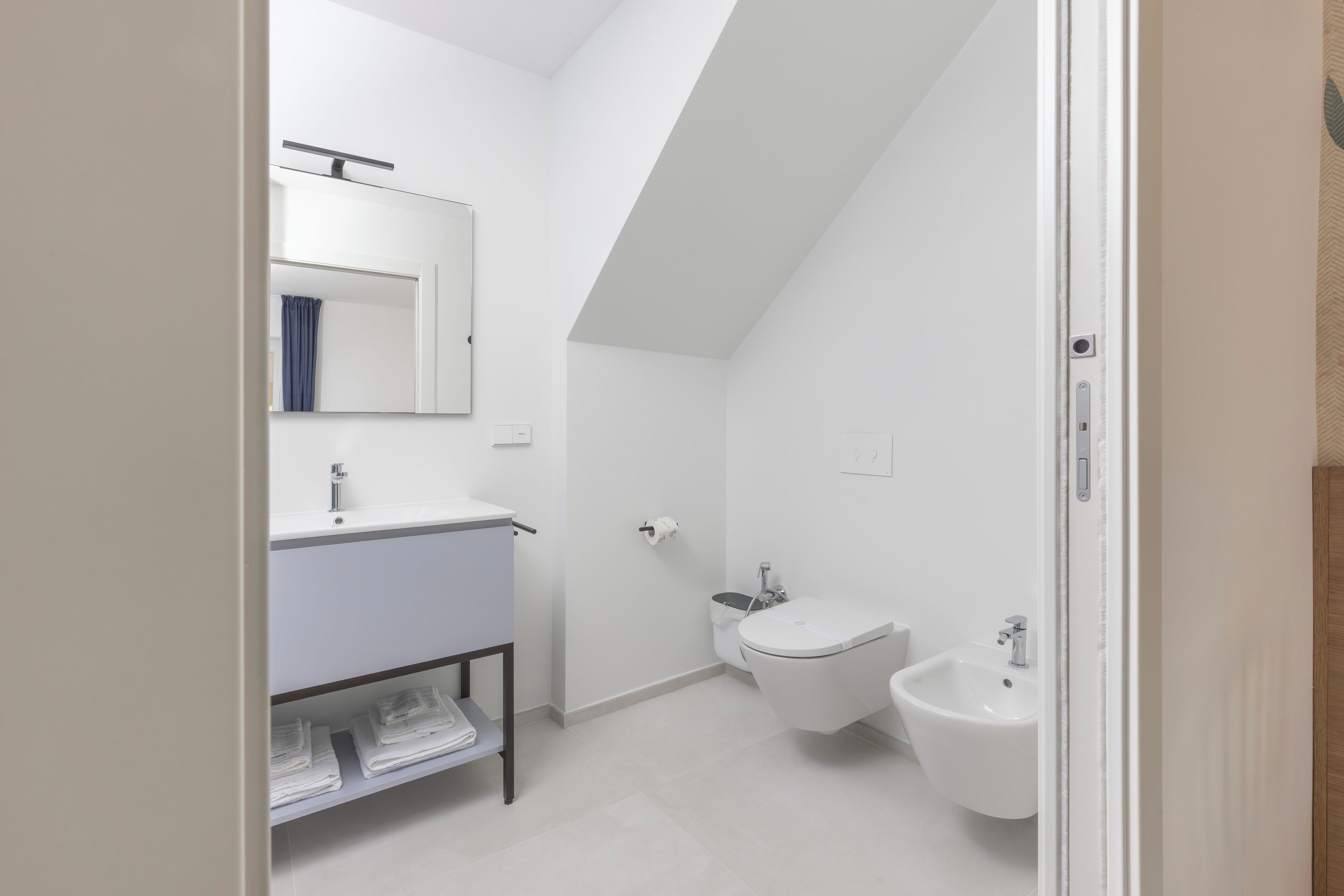 Une salle de bain moderne avec un lavabo blanc, un miroir et un bidet.