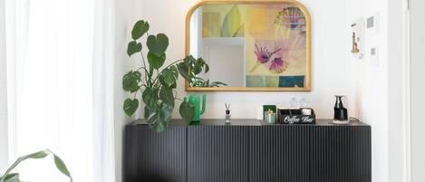 Casa de banho moderna com toucador cinzento escuro, uma planta verde e um canto para café.