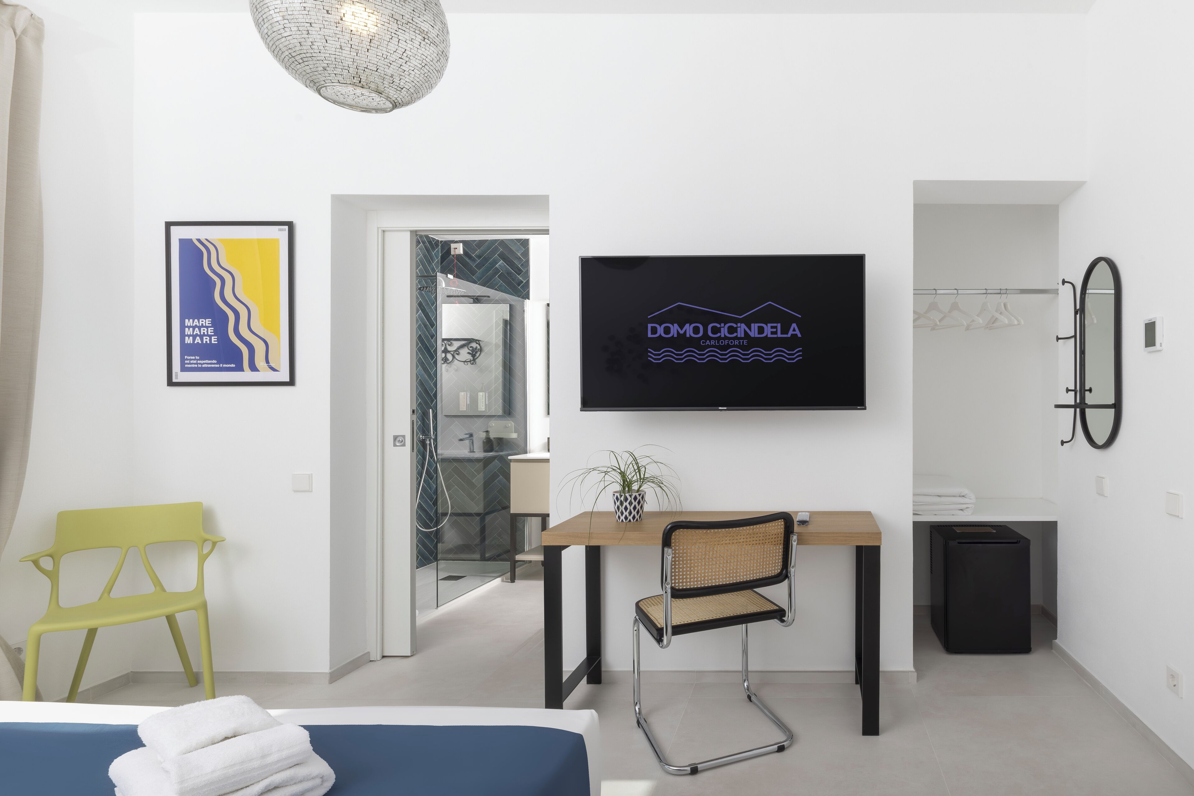 Een moderne hotelkamer met een bed, een bureau, een stoel, een televisie en een douche.
