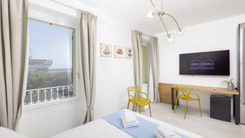 Hotelkamer met een bed, een bureau, twee gele stoelen, een televisie en een raam met gordijnen.