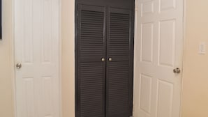 A room with two white doors, one with a black door, and a light switch on the wall.