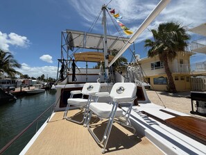 A boat deck with seating, a mast, and a view of the marina. - Southern Cross 40 ft 1977 Marine Trader | Free Kayaks (Monroe County)