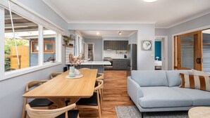 Una cocina moderna con armarios grises, una isla central y un comedor con mesa y sillas de madera.