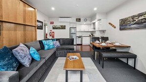 A modern living room with a sofa, coffee table, and dining area.