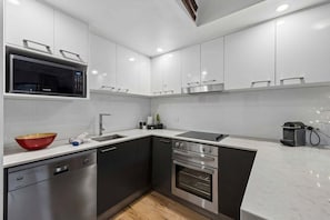 Una cocina moderna con lavavajillas, horno, microondas y un tazón rojo sobre la encimera.