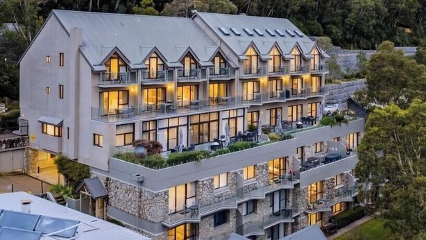 A multi-story hotel with balconies, surrounded by dense forest. - Lantern 07 - Balcony (Thredbo)