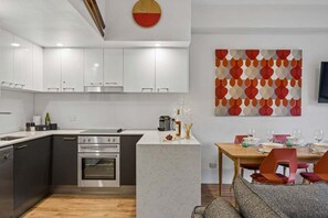 Uma cozinha moderna com armários brancos, forno embutido e área de refeições com mesa e cadeiras.