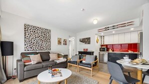 Una sala de estar moderna con un sofá, dos sillones, una mesa de centro y una zona de comedor con una mesa y sillas.