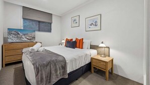 A bedroom with a bed, bedside tables, a dresser, and artwork on the walls.