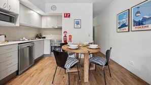A modern kitchen with white cabinets, a microwave, and a dining area with a wooden table and chairs. - Lantern 14 - Terrace (Thredbo)