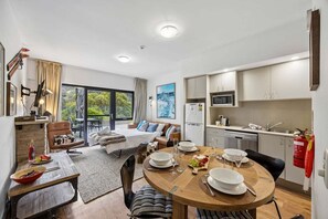 Una stanza moderna e luminosa con un tavolo da pranzo per quattro persone, un letto con vista e un angolo cottura.