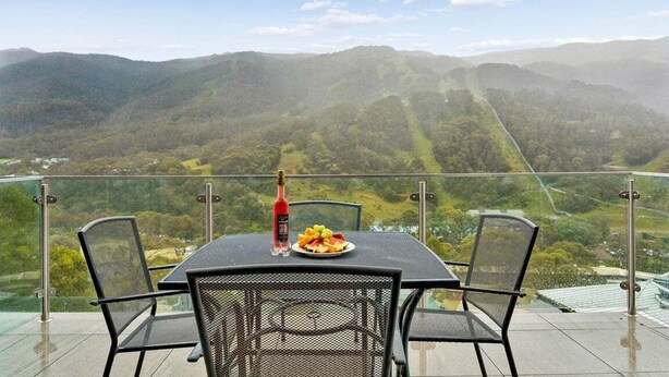 A table with chairs on a balcony overlooking a mountainous landscape. - Lantern 25 - Balcony (Thredbo)