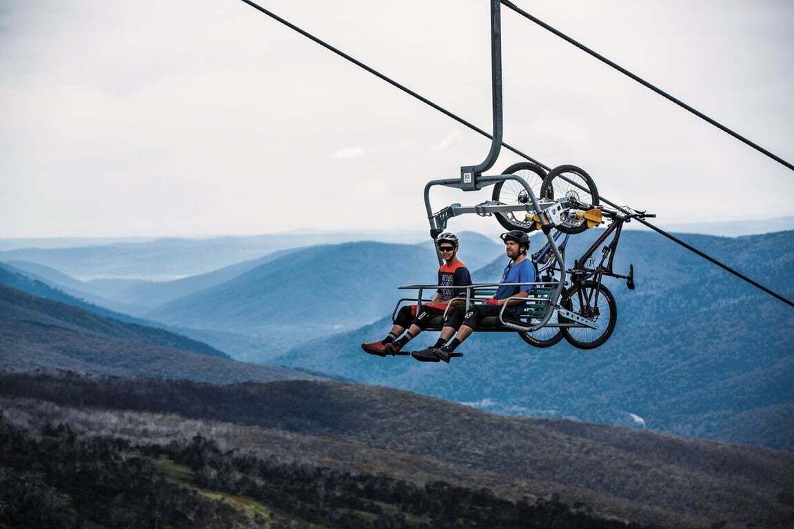 Eine Sesselbahn mit zwei Personen und einem Fahrrad.