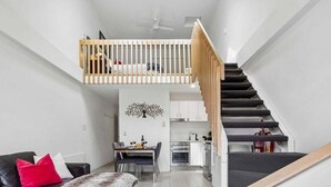 A modern apartment with a loft bedroom, a dining area, and a kitchen.