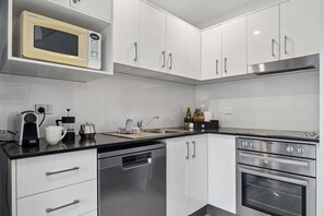 A modern kitchen with white cabinets, a microwave, a coffee maker, a sink, and a dishwasher.