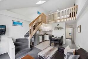 A modern interior with a staircase, kitchen, dining area, and living room.
