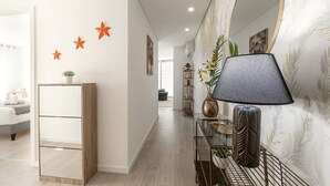 A modern hallway with a wooden cabinet, a mirror, and decorative stars on the wall. - Atlantic Pearl – 5 min to the beach w/ parking (Nazaré)