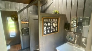 Un baño rústico con pared de madera, un lavamanos y un cartel que enumera animales del bosque.