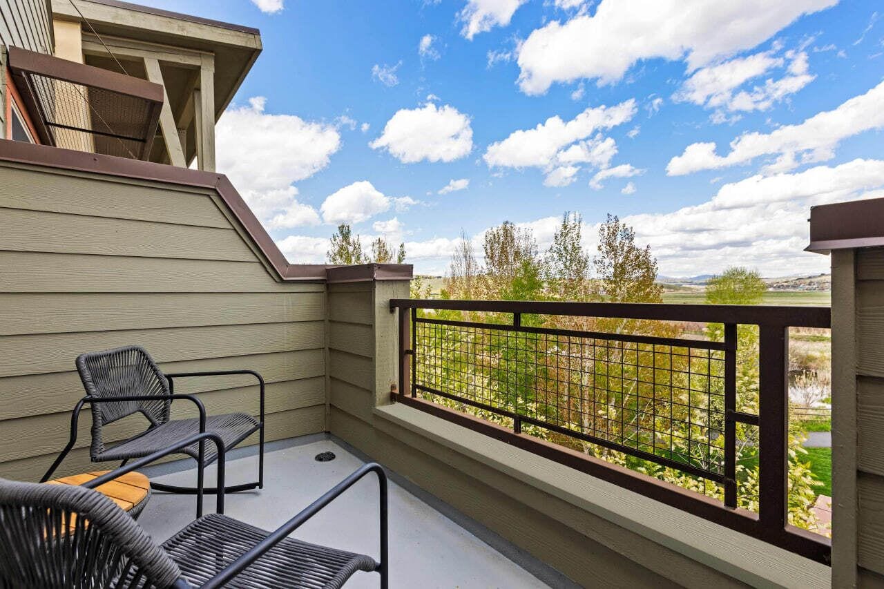 A balcony with a view of a garden and distant landscape.