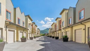 Una hilera de casas adosadas con puertas de garaje, plantas en macetas y una montaña al fondo.