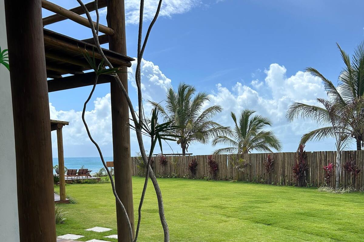 A wooden deck with a view of a well-maintained lawn and a wooden fence.
