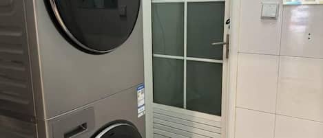 Un lavadero con lavadora, secadora y una puerta con ventanal.