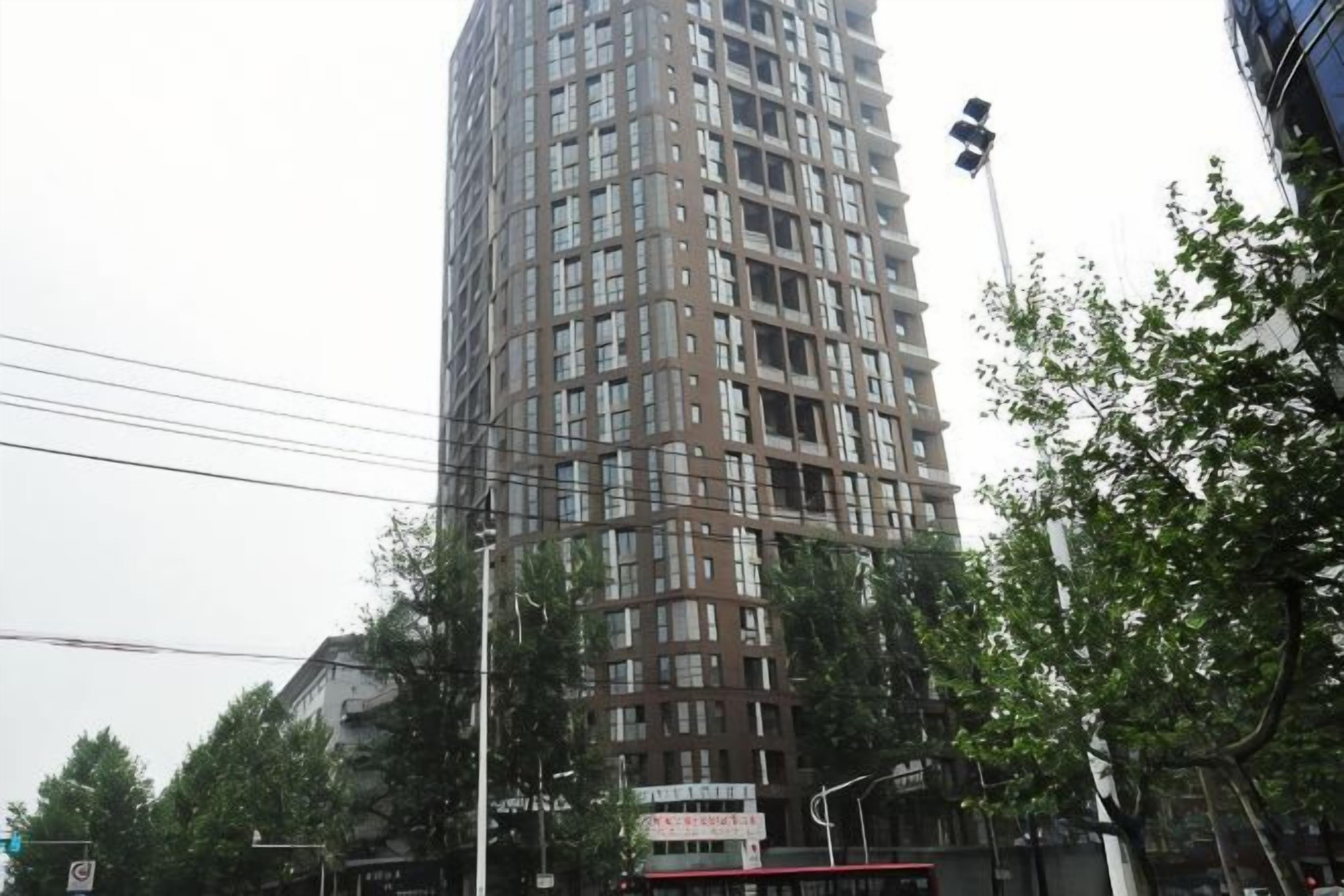 A tall, multi-story building with a grid-like facade, surrounded by trees and streetlights.