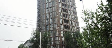 A tall, multi-story building with a grid-like facade, surrounded by trees and streetlights.