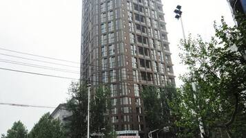 A tall, multi-story building with a grid-like facade, surrounded by trees and street infrastructure.