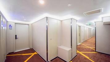 Un couloir d’hôtel avec de nombreuses chambres, un sol recouvert de moquette et une porte avec une pancarte.