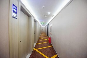A hotel corridor with doors on the left, a fire extinguisher on the right, and a sign indicating a room number. - Zuo'an Hotel (Shijiazhuang North Station, Provincial People's Hospital Branch) (Shijiazhuang)