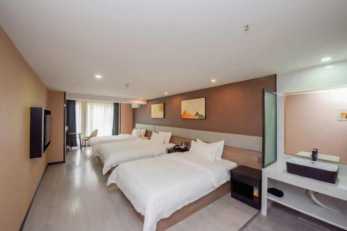 Une chambre d’hôtel avec deux lits, une télévision, un bureau et une salle de bain équipée d’un miroir et d’un lavabo.